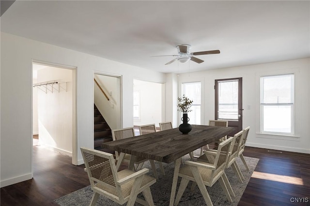 dining space featuring stairs, baseboards, dark wood finished floors, and ceiling fan