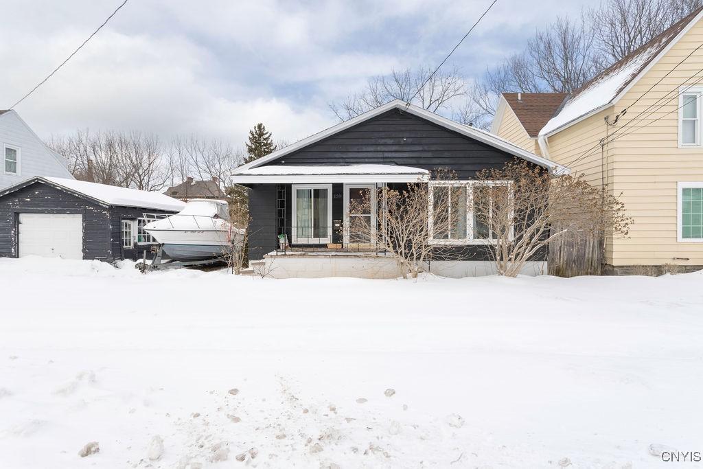 view of front facade with a porch, a garage, and an outbuilding