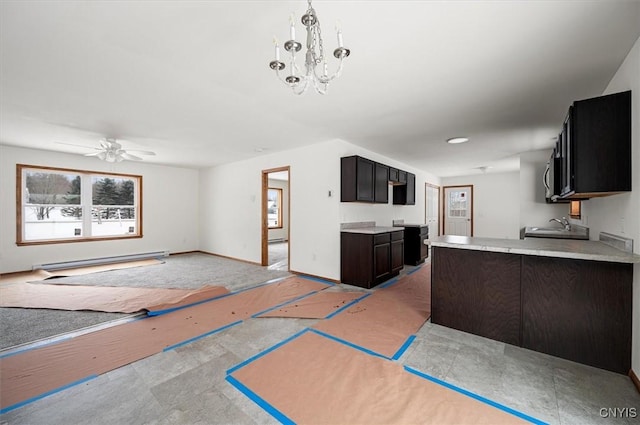 kitchen featuring sink, baseboard heating, hanging light fixtures, dark brown cabinetry, and ceiling fan with notable chandelier