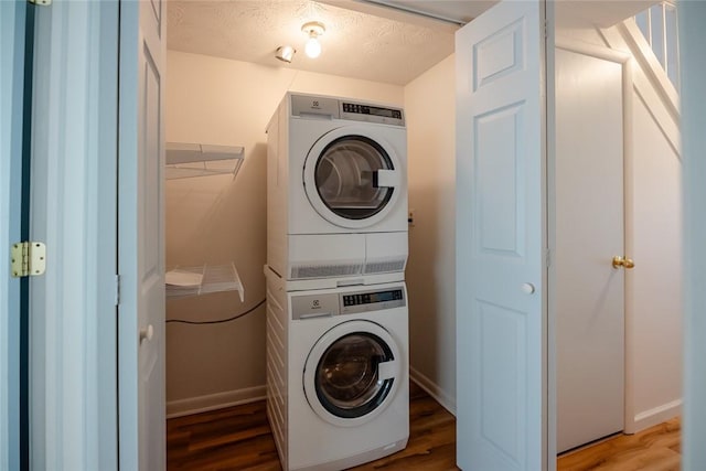 washroom with stacked washer and dryer, dark wood-type flooring, and a textured ceiling