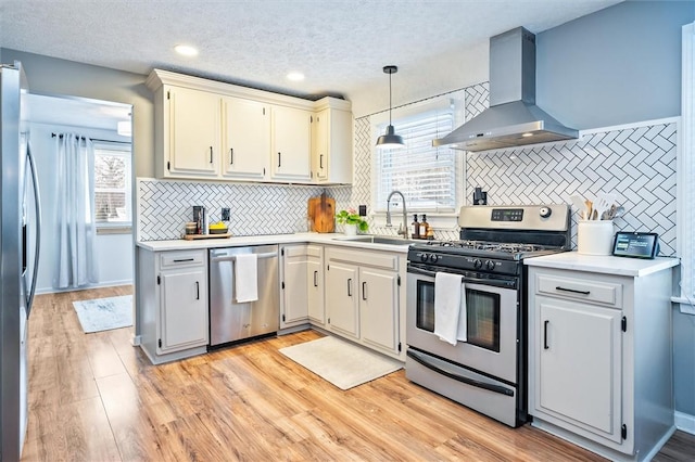 kitchen featuring sink, tasteful backsplash, island range hood, decorative light fixtures, and stainless steel appliances