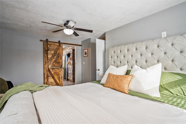 bedroom featuring a barn door, a textured ceiling, and ceiling fan