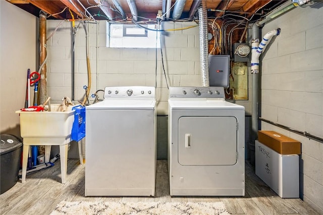 laundry area featuring wood-type flooring, electric panel, and washing machine and dryer