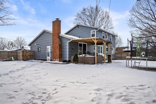 snow covered back of property featuring a trampoline