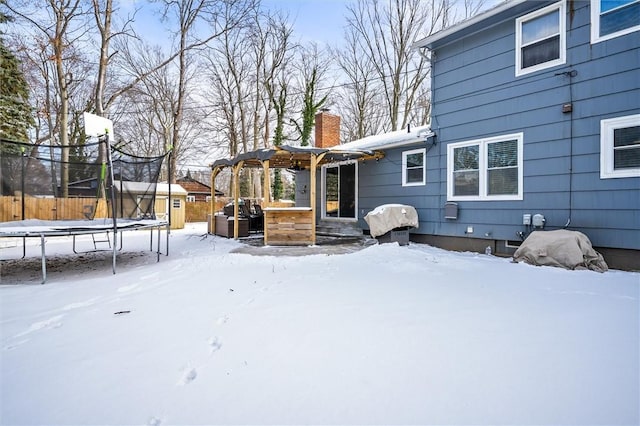 yard covered in snow with a trampoline, a jacuzzi, and a storage unit