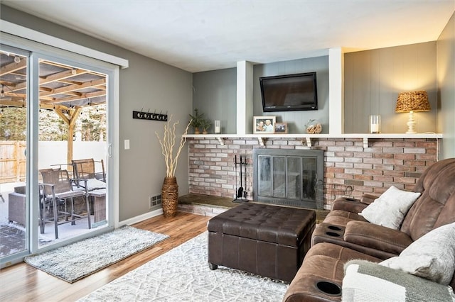 living room with a brick fireplace and wood-type flooring