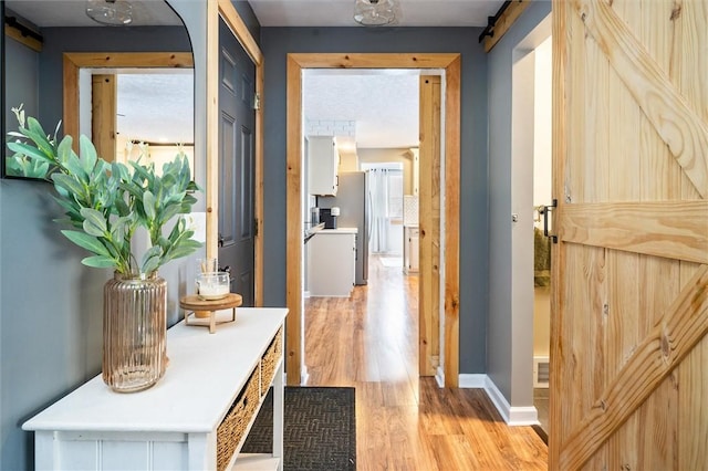 hallway with a barn door, a wealth of natural light, and light hardwood / wood-style floors