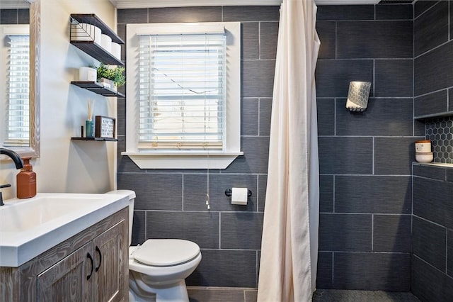 bathroom featuring vanity, toilet, curtained shower, and tile walls