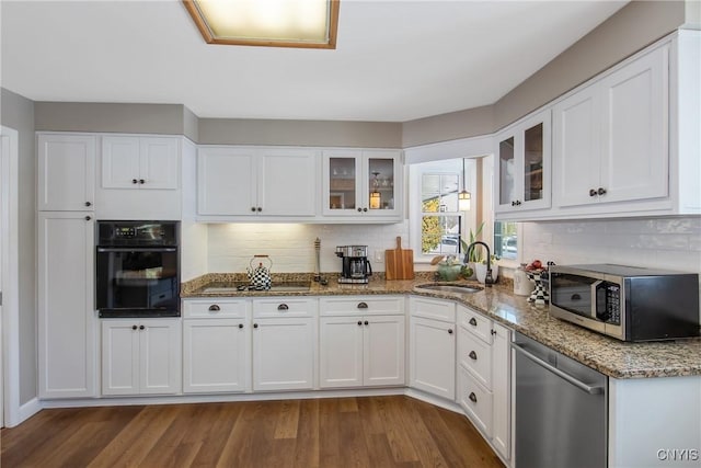 kitchen featuring sink, white cabinetry, dark hardwood / wood-style floors, black appliances, and stone countertops