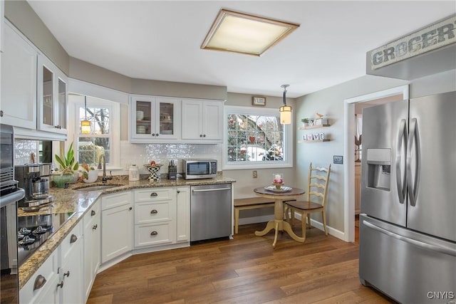 kitchen featuring sink, white cabinetry, hanging light fixtures, appliances with stainless steel finishes, and dark hardwood / wood-style floors