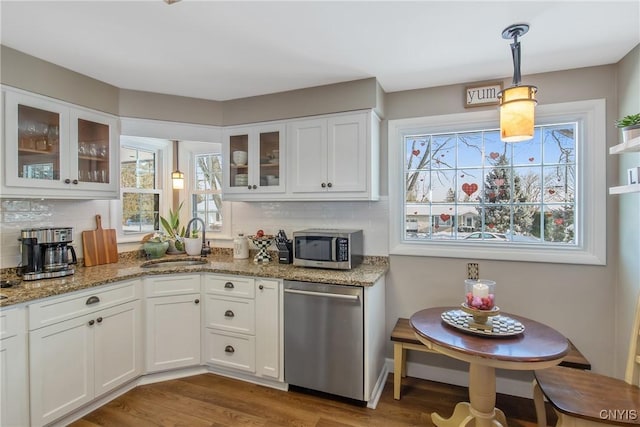 kitchen featuring white cabinetry, stainless steel appliances, sink, and hanging light fixtures