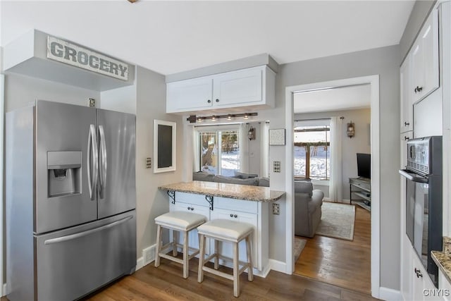 kitchen featuring white cabinets, light stone countertops, and stainless steel fridge