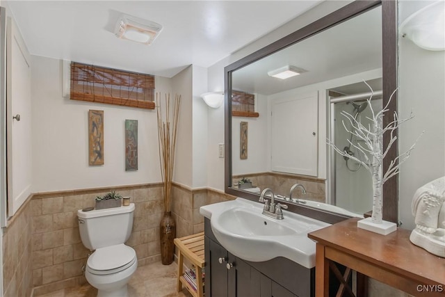 bathroom with tile walls, vanity, tile patterned floors, and toilet