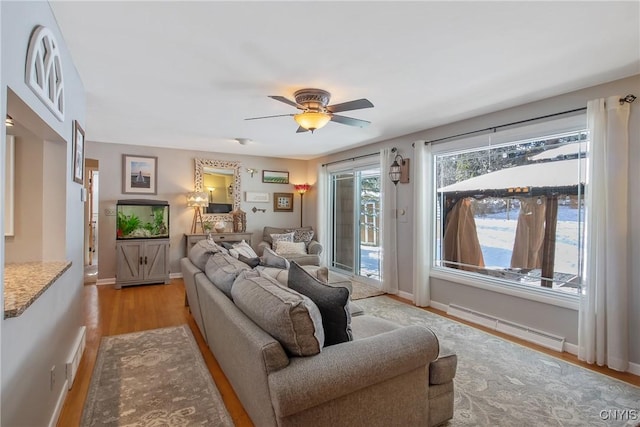 living room with a baseboard radiator, light hardwood / wood-style floors, and ceiling fan