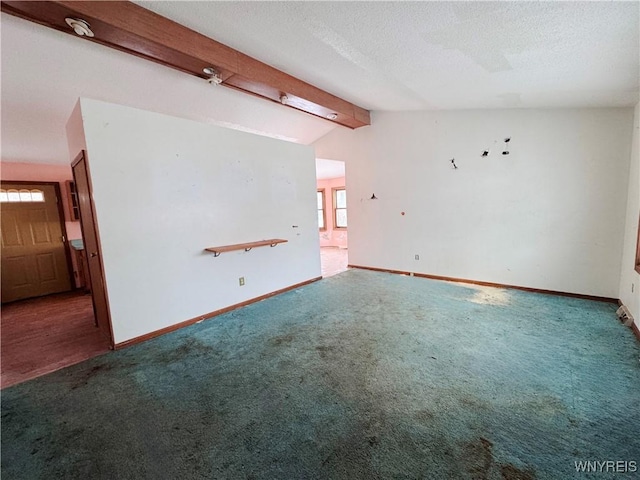 empty room featuring lofted ceiling with beams, carpet, baseboards, and a textured ceiling