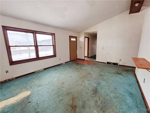 empty room featuring visible vents, carpet flooring, vaulted ceiling, a textured ceiling, and baseboards