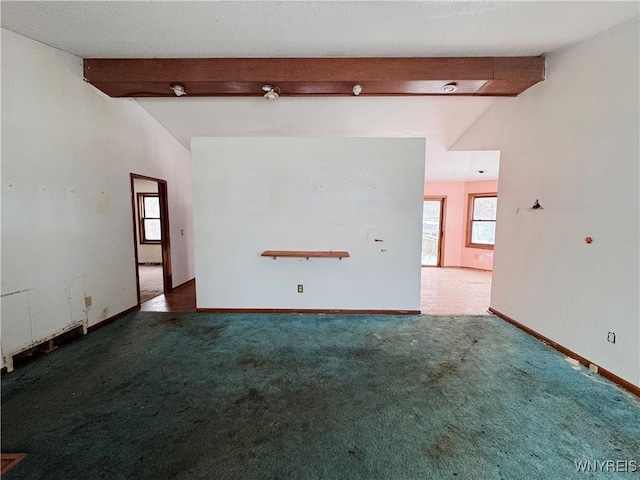 unfurnished room featuring vaulted ceiling with beams, baseboards, and dark carpet