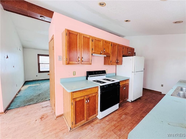 kitchen featuring range with electric cooktop, light wood-style floors, light countertops, freestanding refrigerator, and brown cabinetry