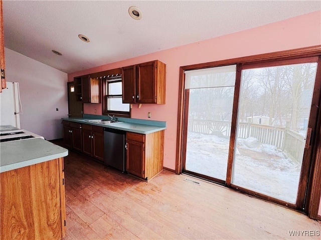 kitchen featuring dishwasher, freestanding refrigerator, light countertops, light wood-style floors, and a sink