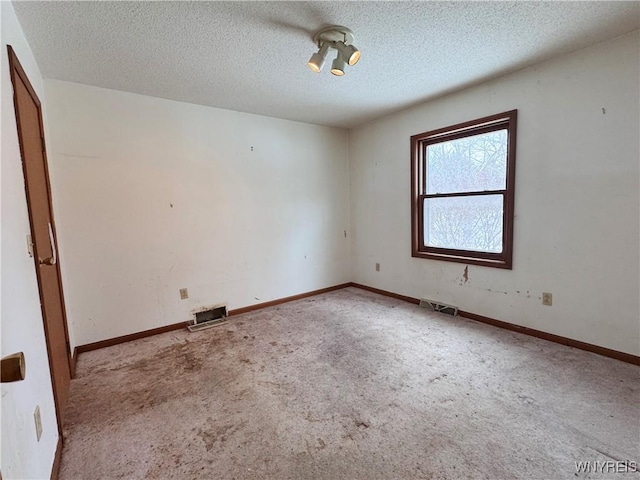 spare room with light carpet, a textured ceiling, and baseboards