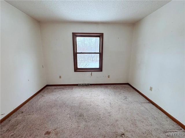 carpeted spare room with visible vents, a textured ceiling, and baseboards