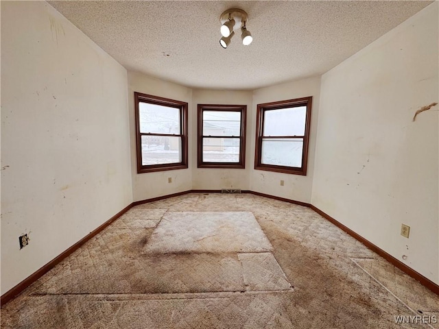 unfurnished room with light carpet, baseboards, and a textured ceiling