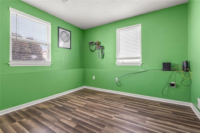 spare room with dark wood-type flooring and a wealth of natural light