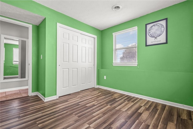 unfurnished bedroom featuring dark wood-type flooring and a closet