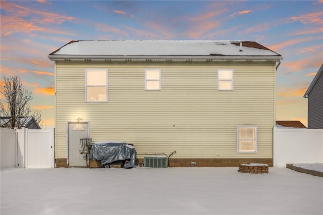 back house at dusk featuring central AC