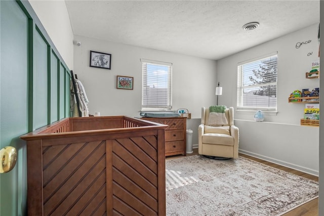 interior space with hardwood / wood-style flooring, a nursery area, and a textured ceiling