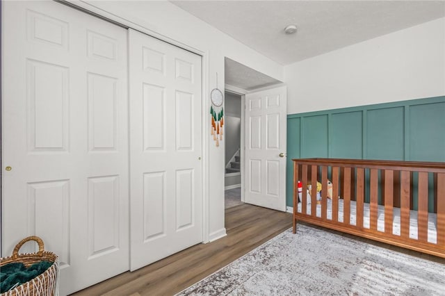 bedroom featuring hardwood / wood-style floors, a closet, and a nursery area