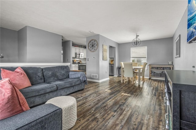 living room featuring an inviting chandelier and dark hardwood / wood-style flooring