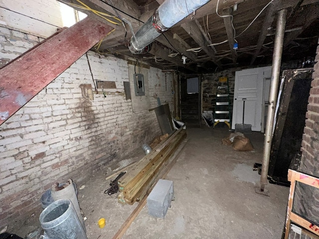 basement featuring electric panel and brick wall