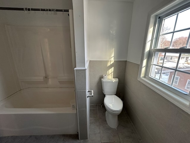 bathroom featuring toilet, tile patterned flooring, and tile walls