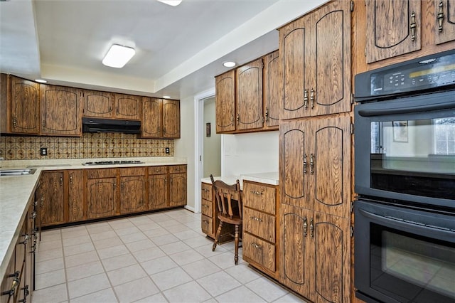 kitchen featuring light tile patterned floors, gas cooktop, double oven, backsplash, and a raised ceiling