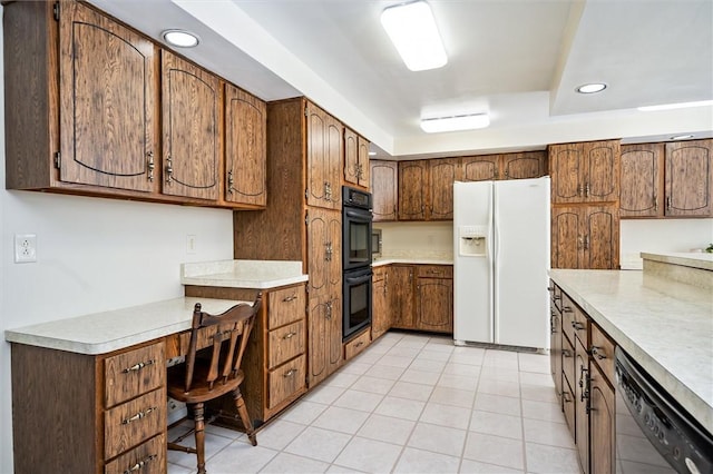 kitchen with a raised ceiling, built in desk, light tile patterned floors, and black appliances