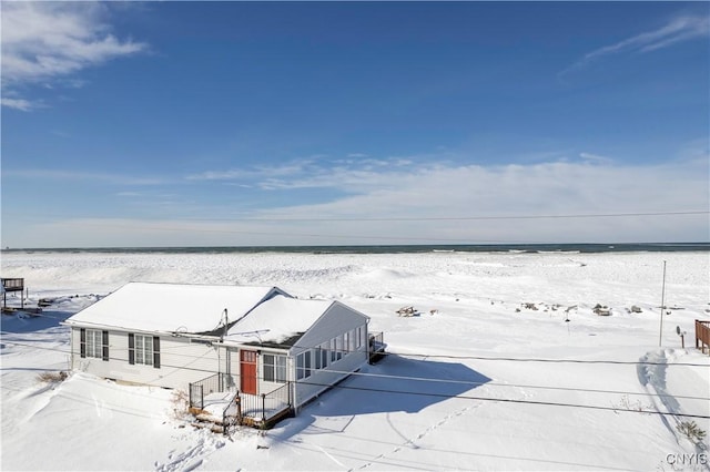 snowy aerial view with a water view and a beach view