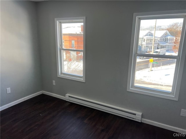 unfurnished room with baseboard heating, plenty of natural light, and dark hardwood / wood-style floors