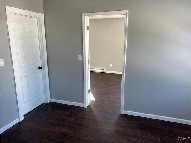 unfurnished room featuring a baseboard radiator and dark hardwood / wood-style floors