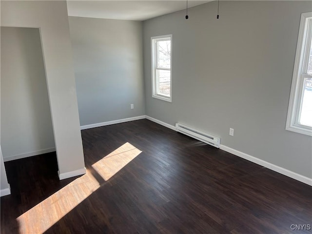 empty room with dark wood-type flooring and a baseboard heating unit