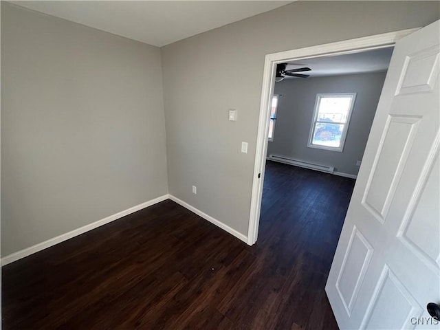 spare room featuring dark hardwood / wood-style flooring, a baseboard radiator, and ceiling fan