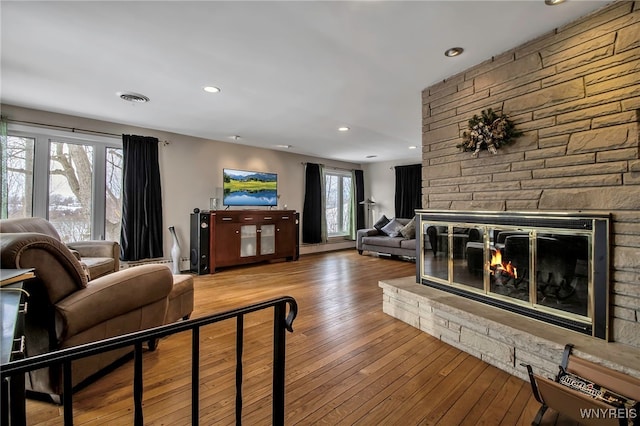 living room with wood-type flooring and a stone fireplace