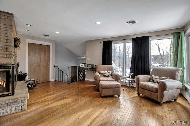 living area with a baseboard heating unit, a fireplace, and light hardwood / wood-style floors