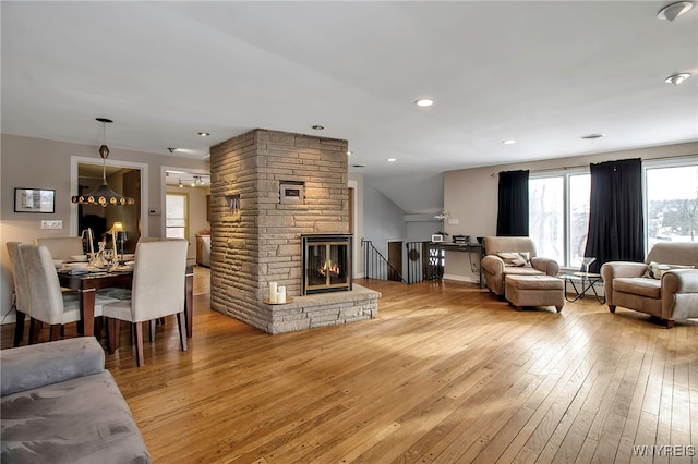 living room featuring a fireplace, light hardwood / wood-style flooring, and vaulted ceiling