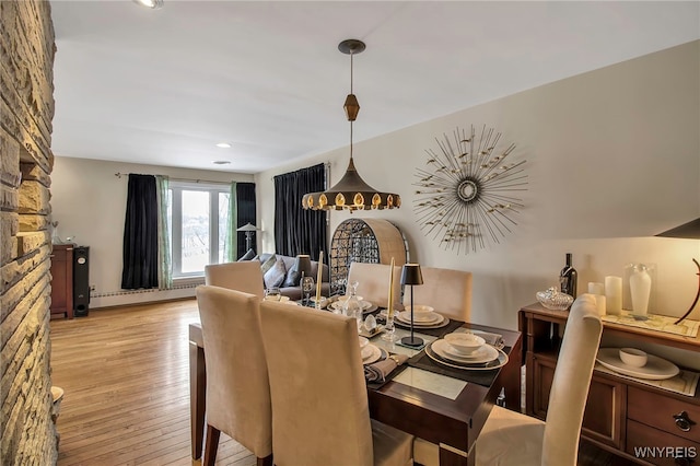 dining area with a baseboard heating unit and light wood-type flooring