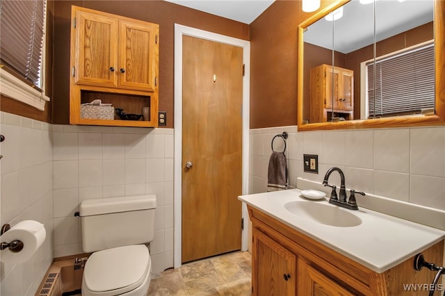 bathroom featuring vanity, tile walls, and toilet