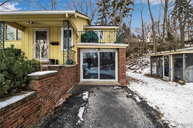 snow covered property entrance featuring a balcony