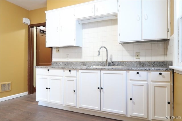 kitchen with light stone countertops, decorative backsplash, and white cabinets