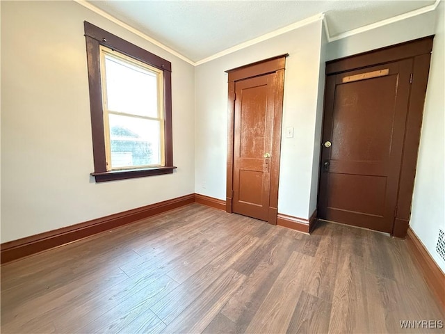 unfurnished bedroom featuring crown molding, a closet, and hardwood / wood-style flooring