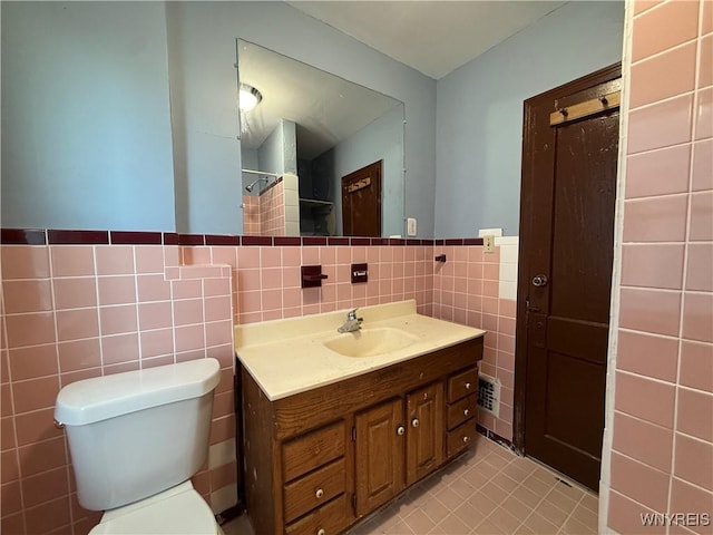 bathroom with vanity, tile walls, tile patterned floors, and toilet